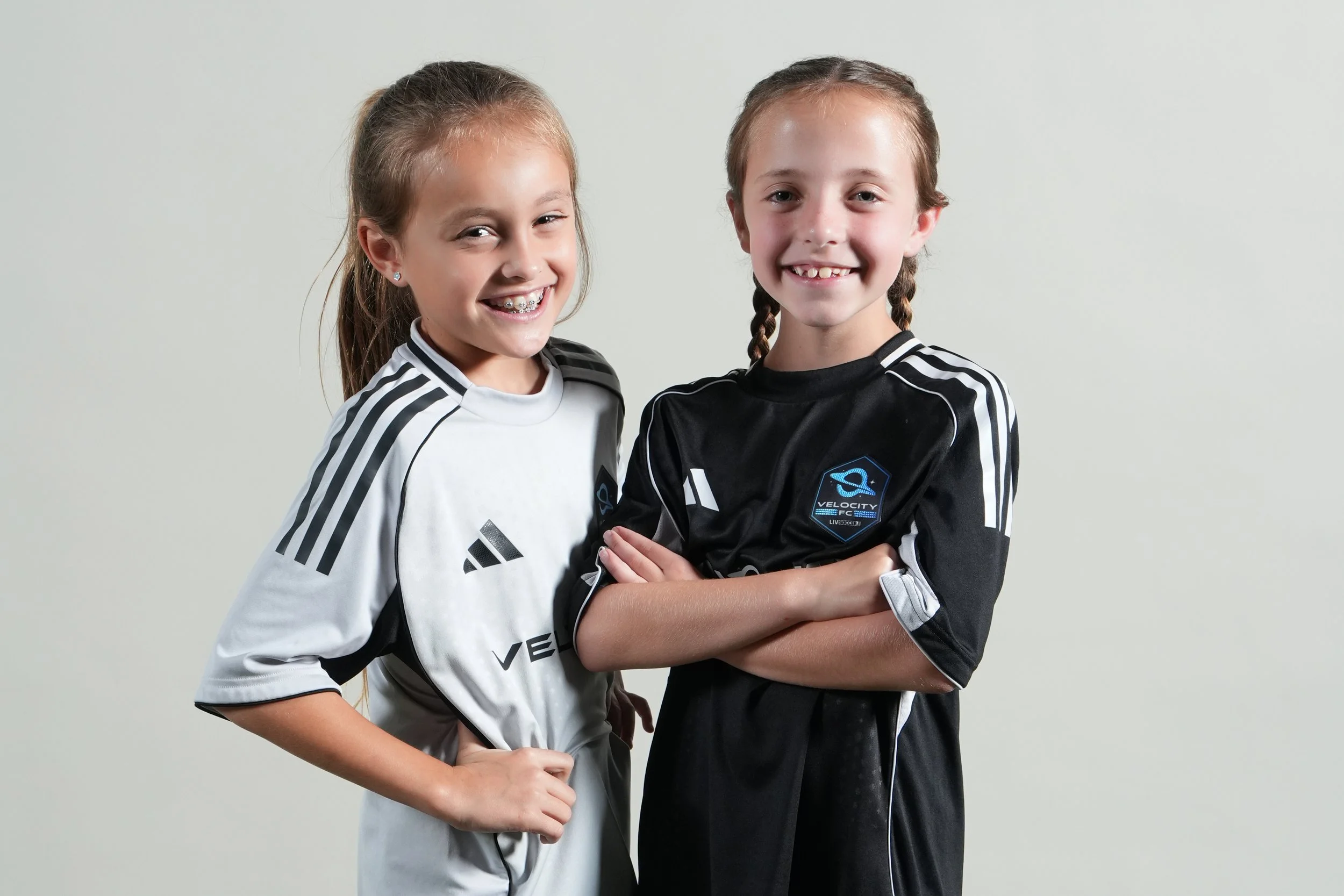 Two young players in G League kits, arms crossed and smiling